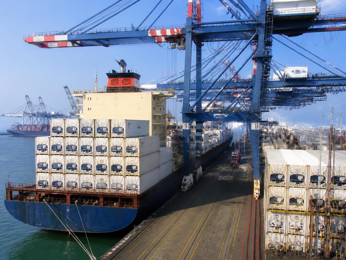 Container ship loaded with stacked refrigerated reefer containers at an international port terminal